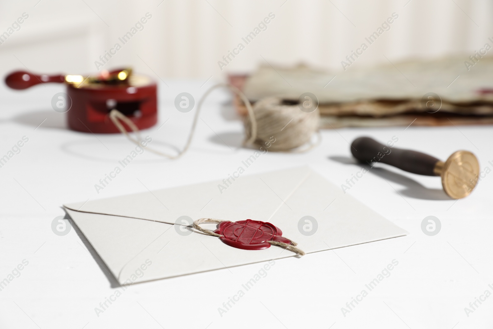Envelope with wax seal and stamp on white wooden table, closeup Photo of Envelope with wax seal and stamp on white wooden table, closeup