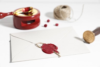 Photo of Envelope with wax seal and stamp on white wooden table, closeup