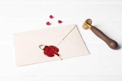 Photo of Envelope with wax seal and stamp on white wooden table, closeup