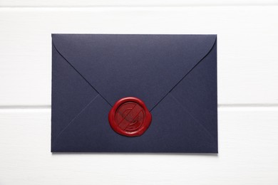 Photo of Envelope with wax seal on white wooden table, top view