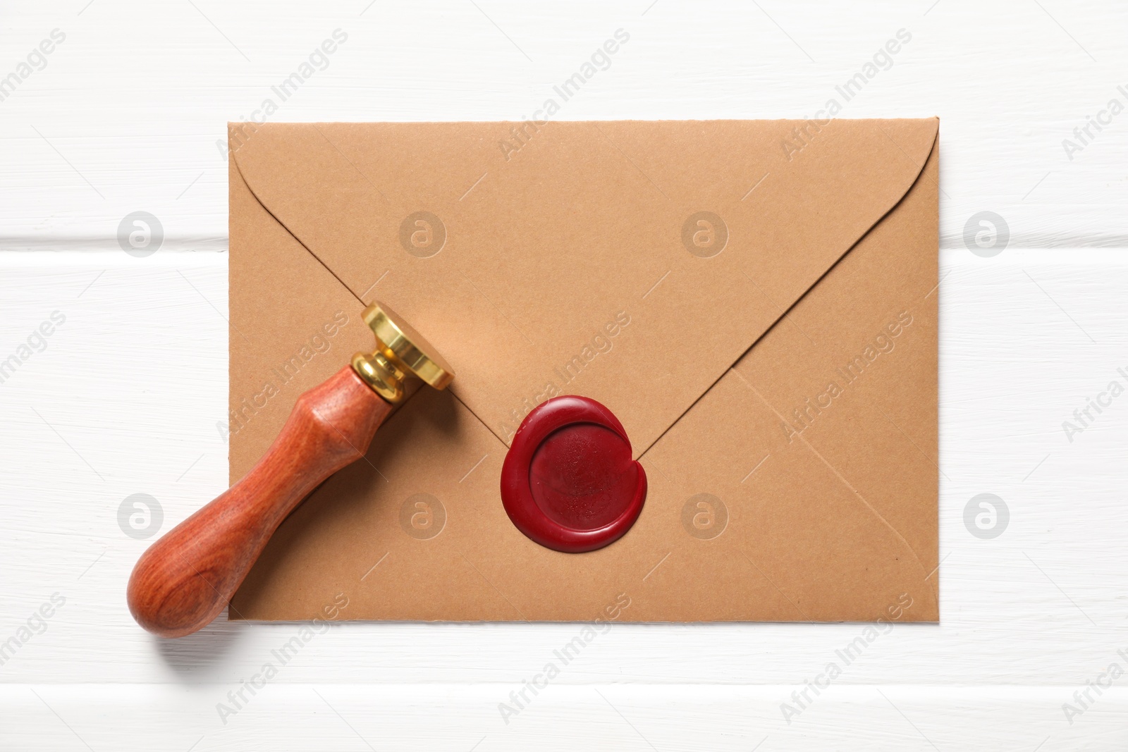 Envelope with wax seal and stamp on white wooden table, top view Photo of Envelope with wax seal and stamp on white wooden table, top view