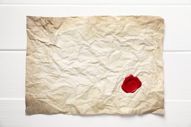 Photo of Crumpled paper with wax seal on white wooden table, top view