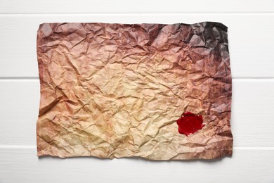 Photo of Crumpled paper with wax seal on white wooden table, top view