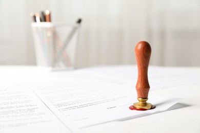 Photo of Documents with wax seal and stamp on white table, closeup
