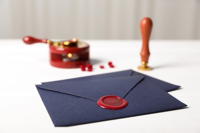 Photo of Envelopes with wax seal and stamp on white table, closeup
