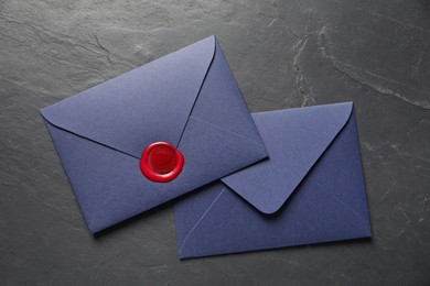 Photo of Envelopes with wax seal on black table, top view