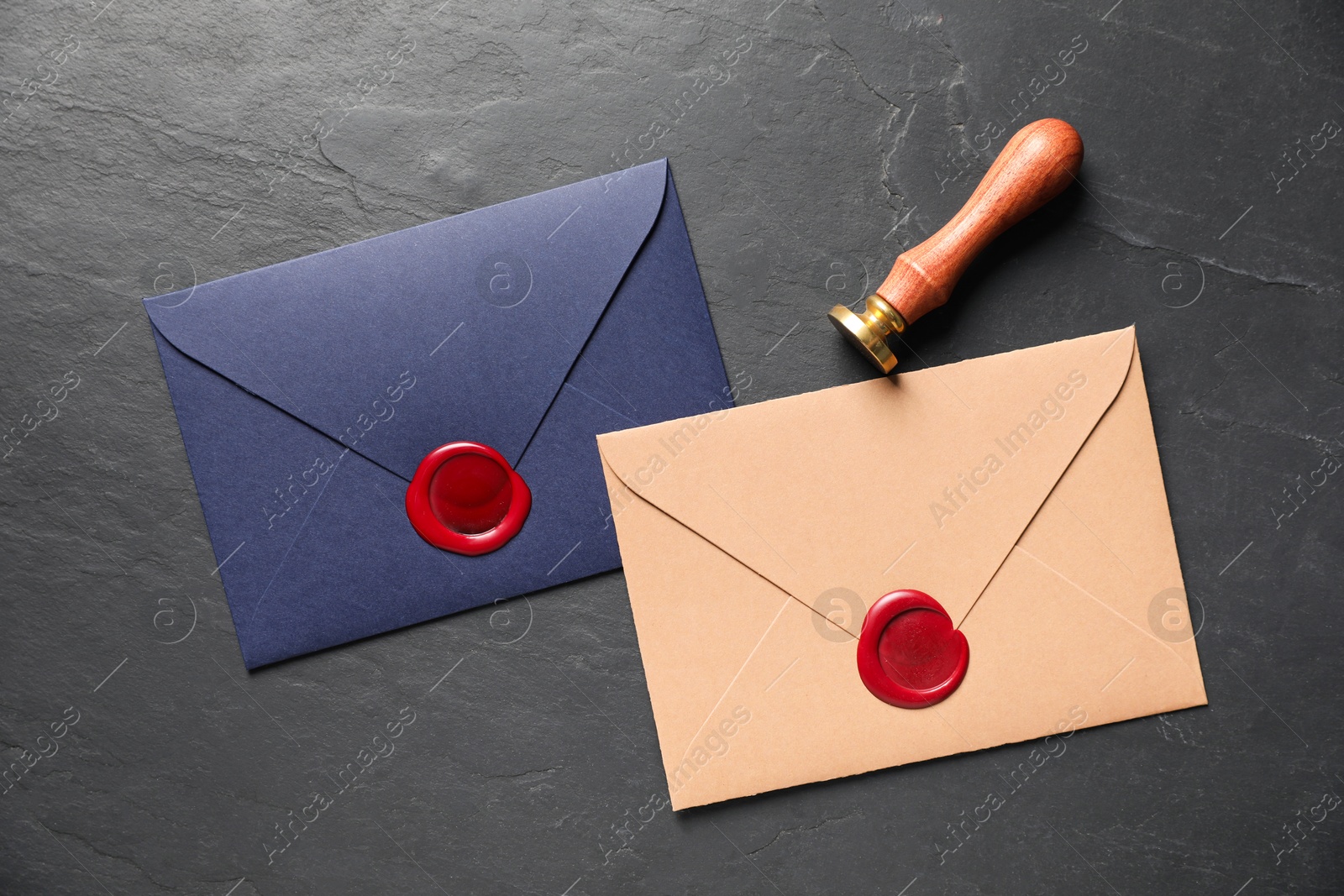 Envelopes with wax seals and stamp on black table, flat lay Photo of Envelopes with wax seals and stamp on black table, flat lay