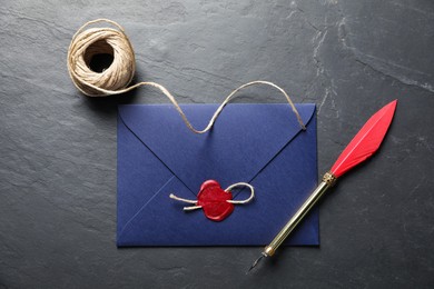 Photo of Envelope with wax seal, twine and fountain pen on black table, flat lay