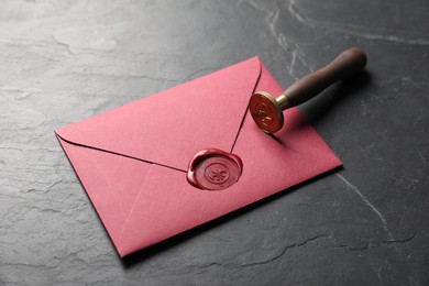 Photo of Envelope with wax seal and stamp on black table, closeup