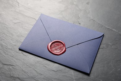 Photo of Envelope with wax seal on black table, closeup