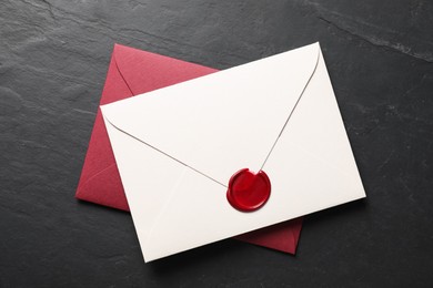 Photo of Envelopes with wax seal on black table, top view