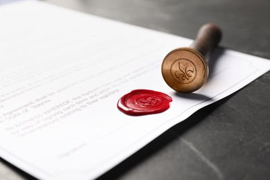 Photo of Document with wax seal and stamp on black table, closeup