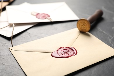 Photo of Envelopes with wax seals and stamp on black table, closeup