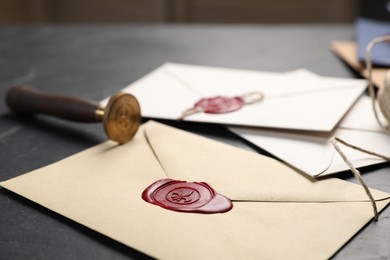 Photo of Envelopes with wax seals and stamp on black table, closeup