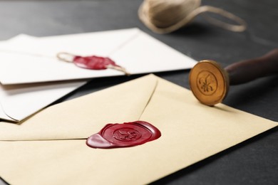 Photo of Envelopes with wax seals and stamp on black table, closeup