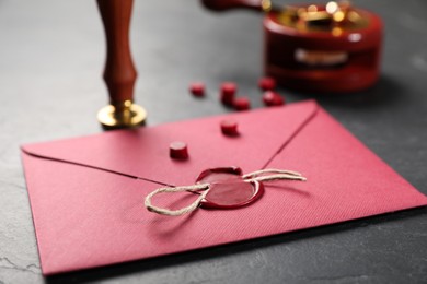 Photo of Envelope with wax seal, twine and stamp on black table, closeup
