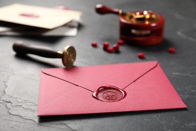 Photo of Envelope with wax seal and stamp on black table, closeup
