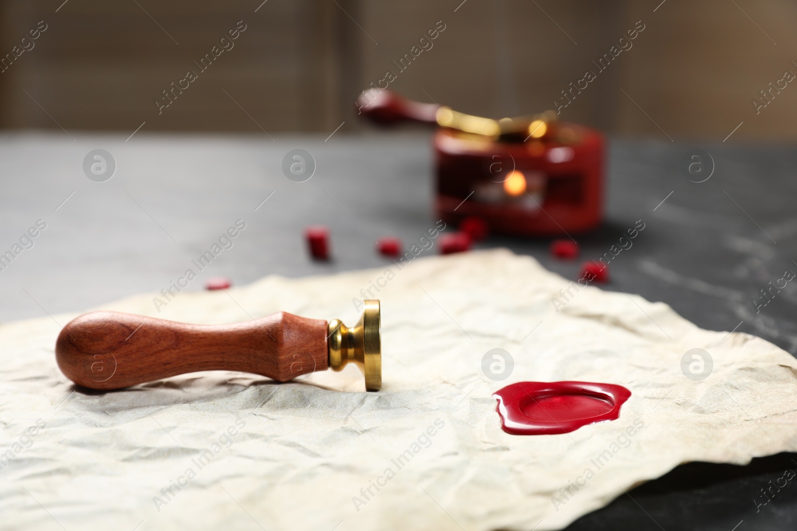 Crumpled paper with wax seal and stamp on black table, closeup Photo of Crumpled paper with wax seal and stamp on black table, closeup