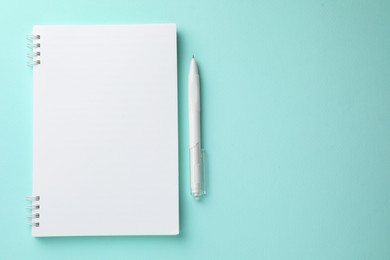 Photo of White notebook and pen on light blue background, flat lay. Space for text