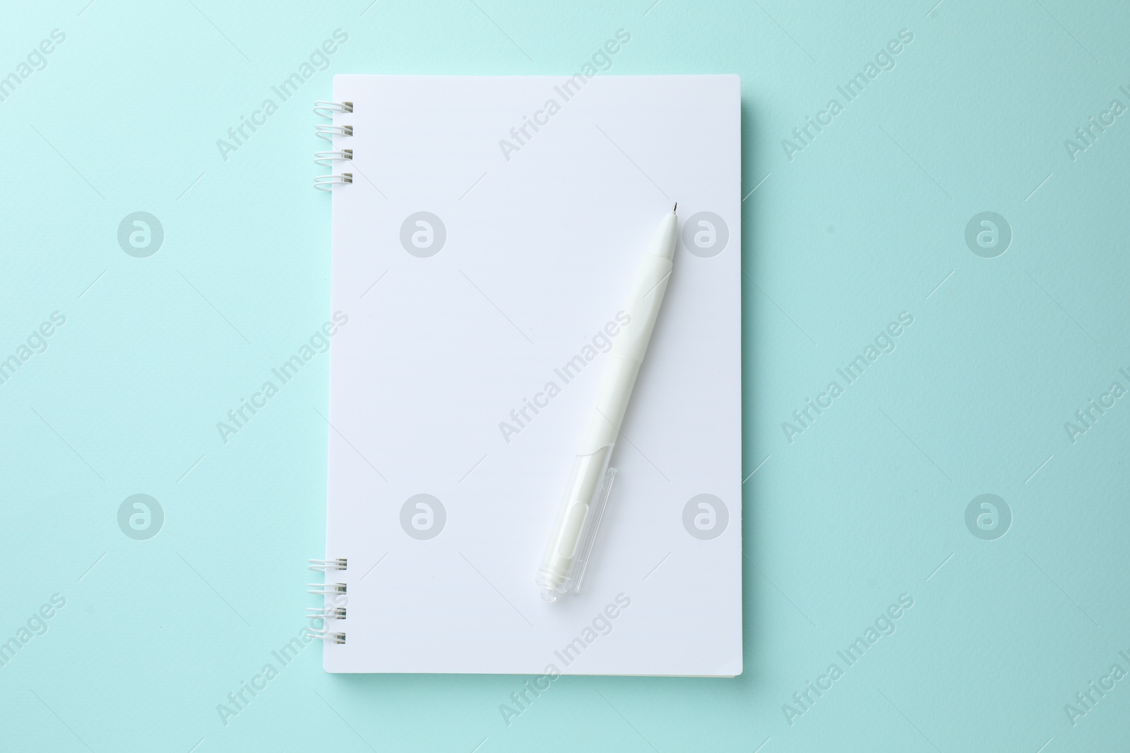 White notebook and pen on light blue background, top view Photo of White notebook and pen on light blue background, top view