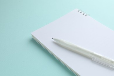 Photo of White notebook and pen on light blue background, closeup. Space for text
