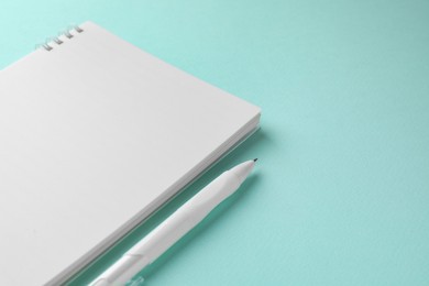 Photo of White notebook and pen on light blue background, closeup. Space for text