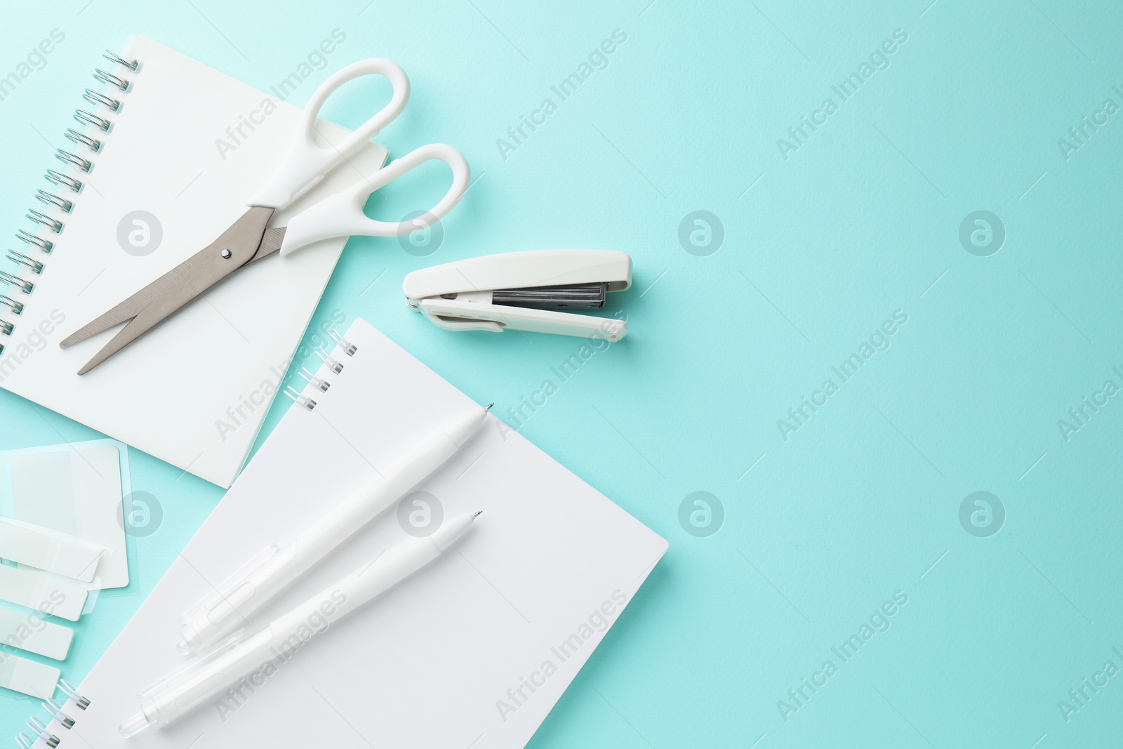 White notebooks and other stationery on light blue background, flat lay. Space for text Photo of White notebooks and other stationery on light blue background, flat lay. Space for text