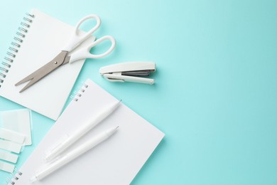 Photo of White notebooks and other stationery on light blue background, flat lay. Space for text
