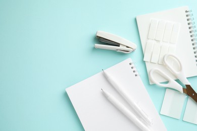 Photo of White notebooks and other stationery on light blue background, flat lay. Space for text