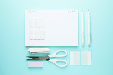 Photo of White notebook and other stationery on light blue background, flat lay