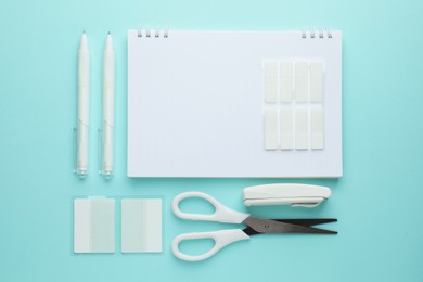 Photo of White notebook and other stationery on light blue background, flat lay