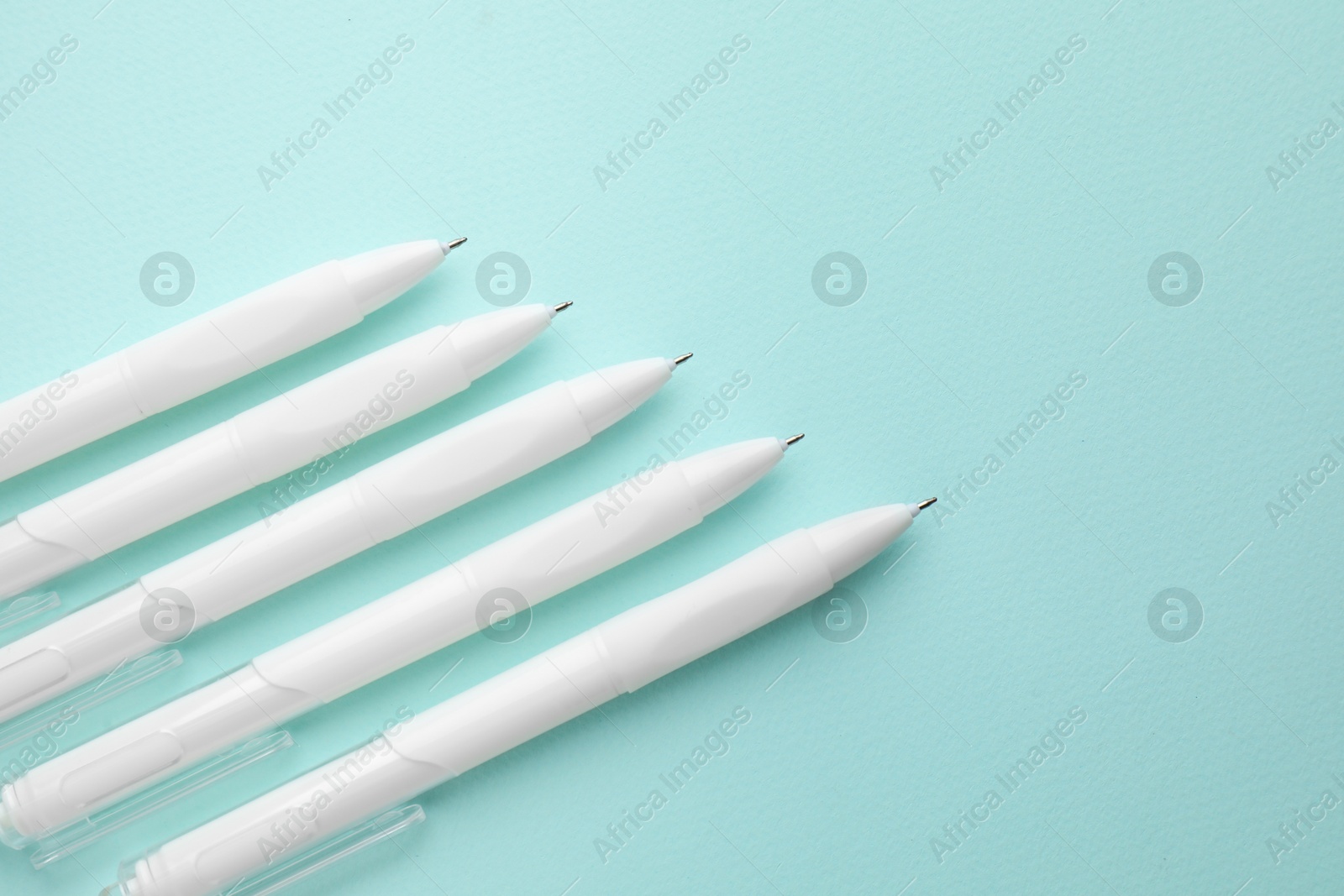 White pens on light blue background, flat lay. Space for text Photo of White pens on light blue background, flat lay. Space for text