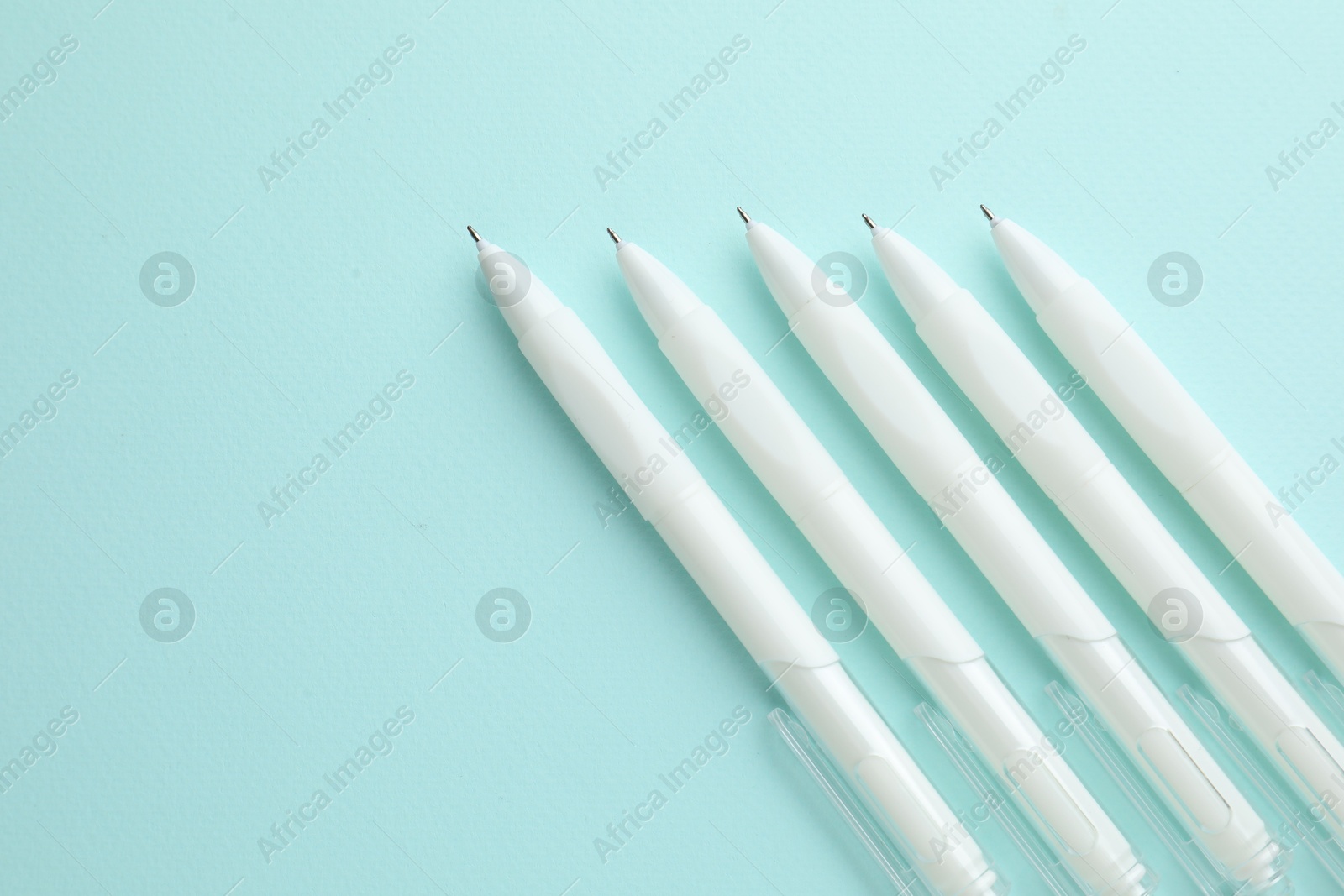 White pens on light blue background, flat lay. Space for text Photo of White pens on light blue background, flat lay. Space for text