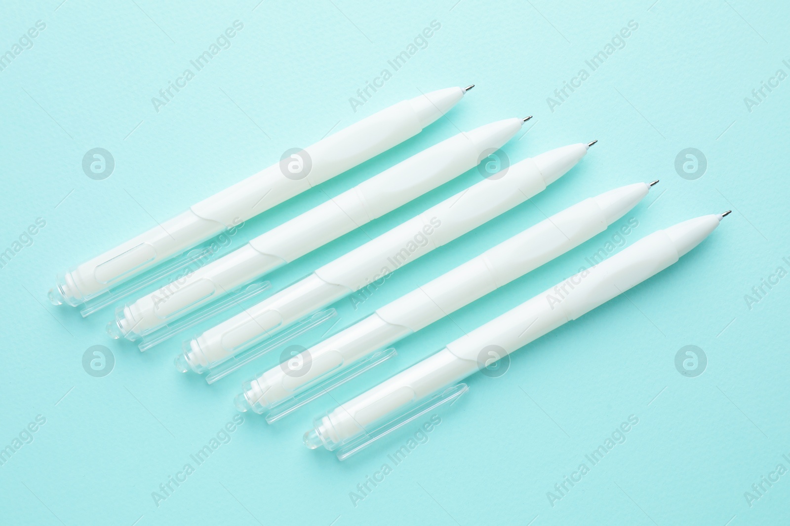 White pens on light blue background, flat lay Photo of White pens on light blue background, flat lay