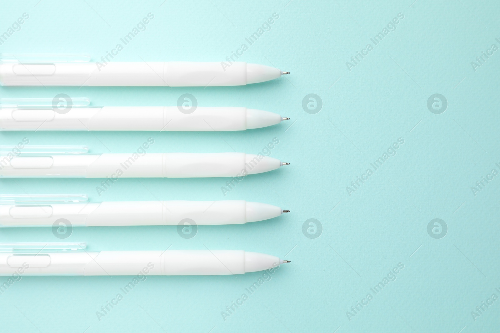 White pens on light blue background, flat lay. Space for text Photo of White pens on light blue background, flat lay. Space for text