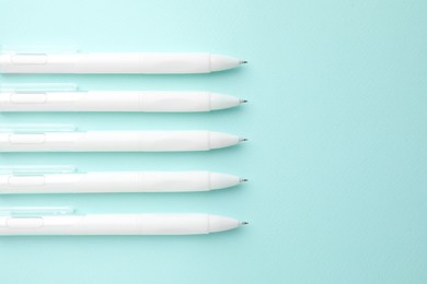 Photo of White pens on light blue background, flat lay. Space for text