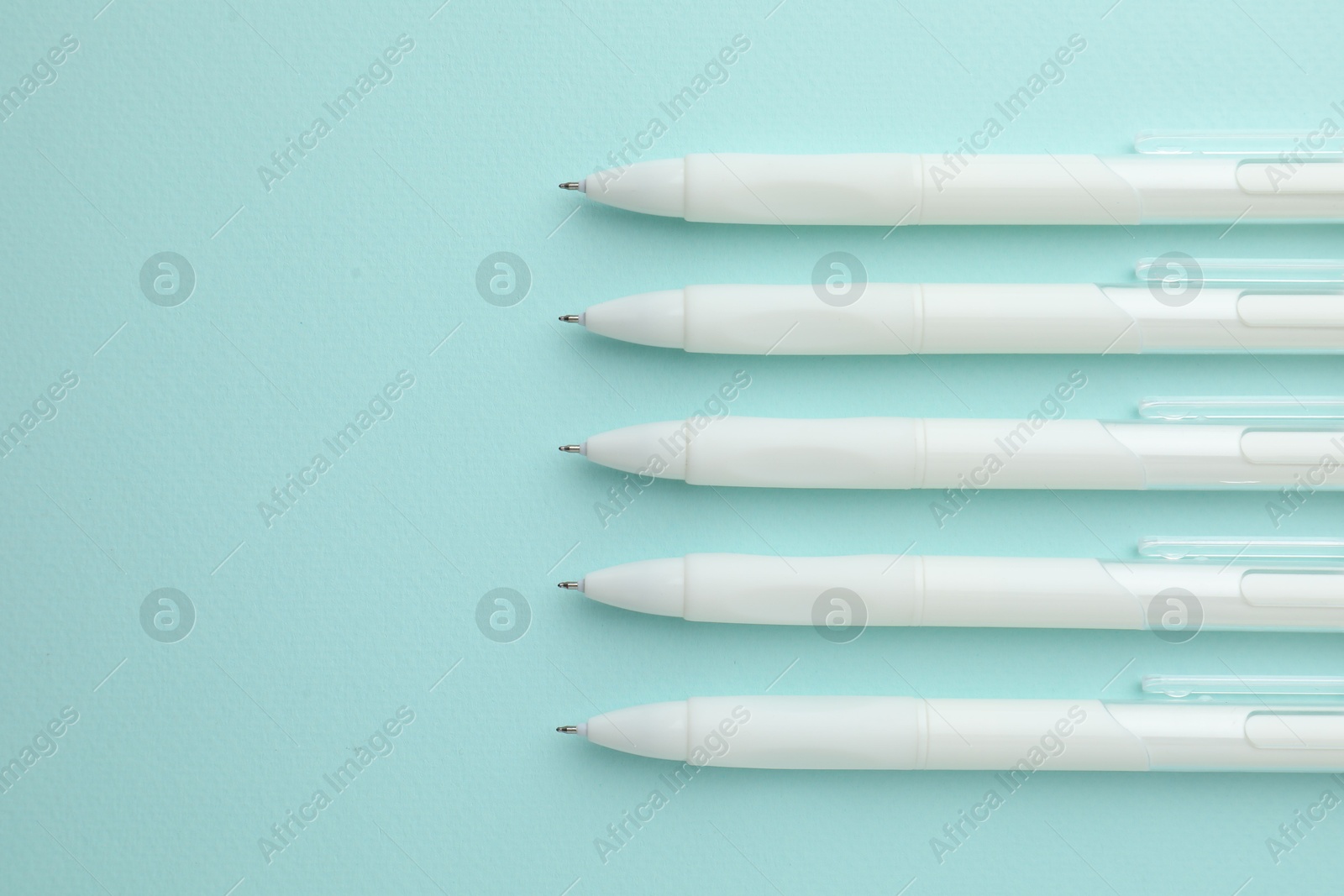 White pens on light blue background, flat lay. Space for text Photo of White pens on light blue background, flat lay. Space for text