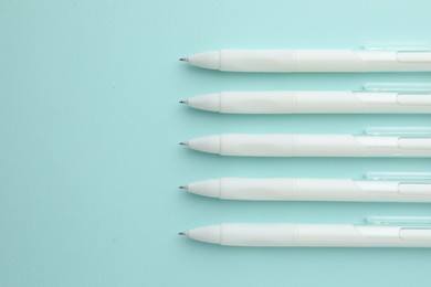 Photo of White pens on light blue background, flat lay. Space for text