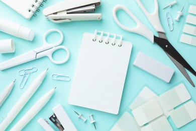 Photo of White notebook and other stationery on light blue background, flat lay