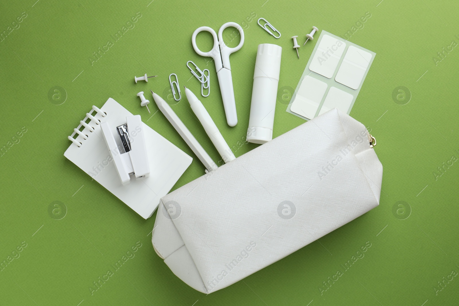 White pencil case and different stationery on green background, flat lay Photo of White pencil case and different stationery on green background, flat lay