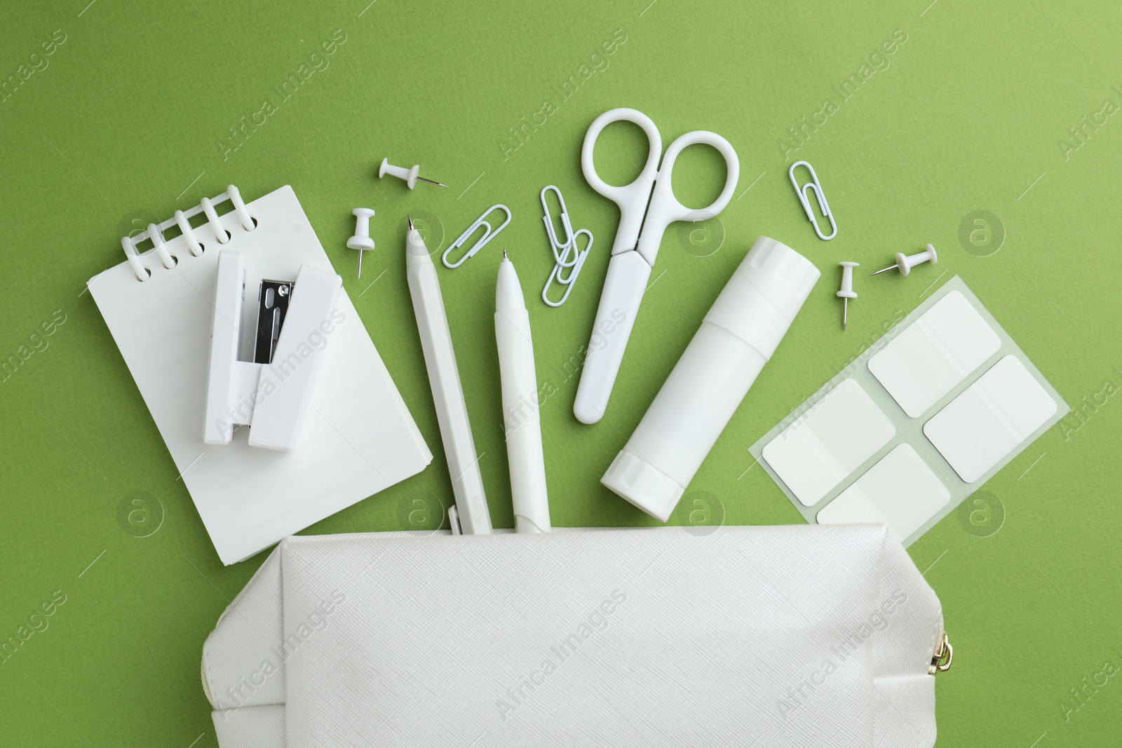 White pencil case and different stationery on green background, flat lay Photo of White pencil case and different stationery on green background, flat lay