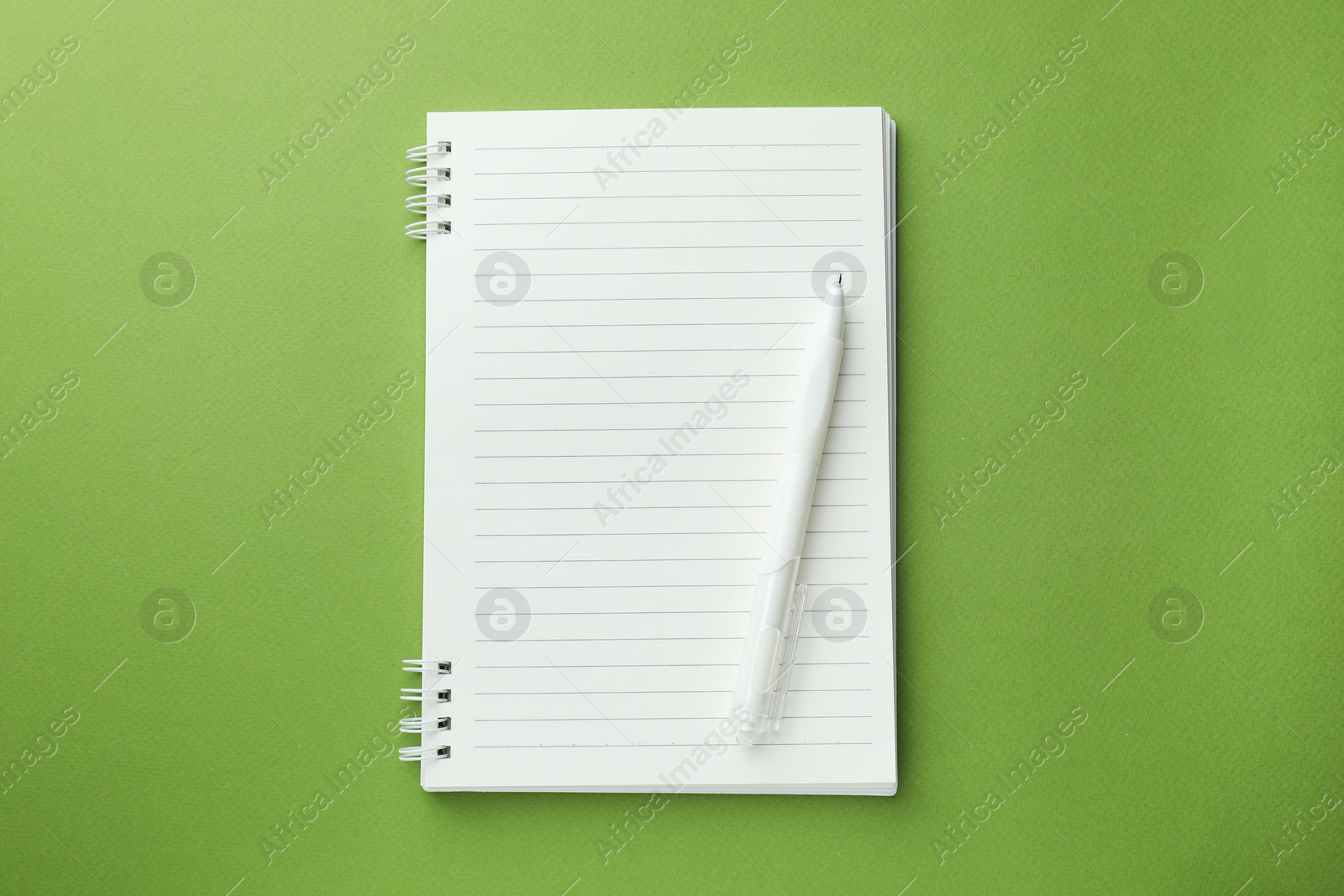 White notebook and pen on green background, top view Photo of White notebook and pen on green background, top view