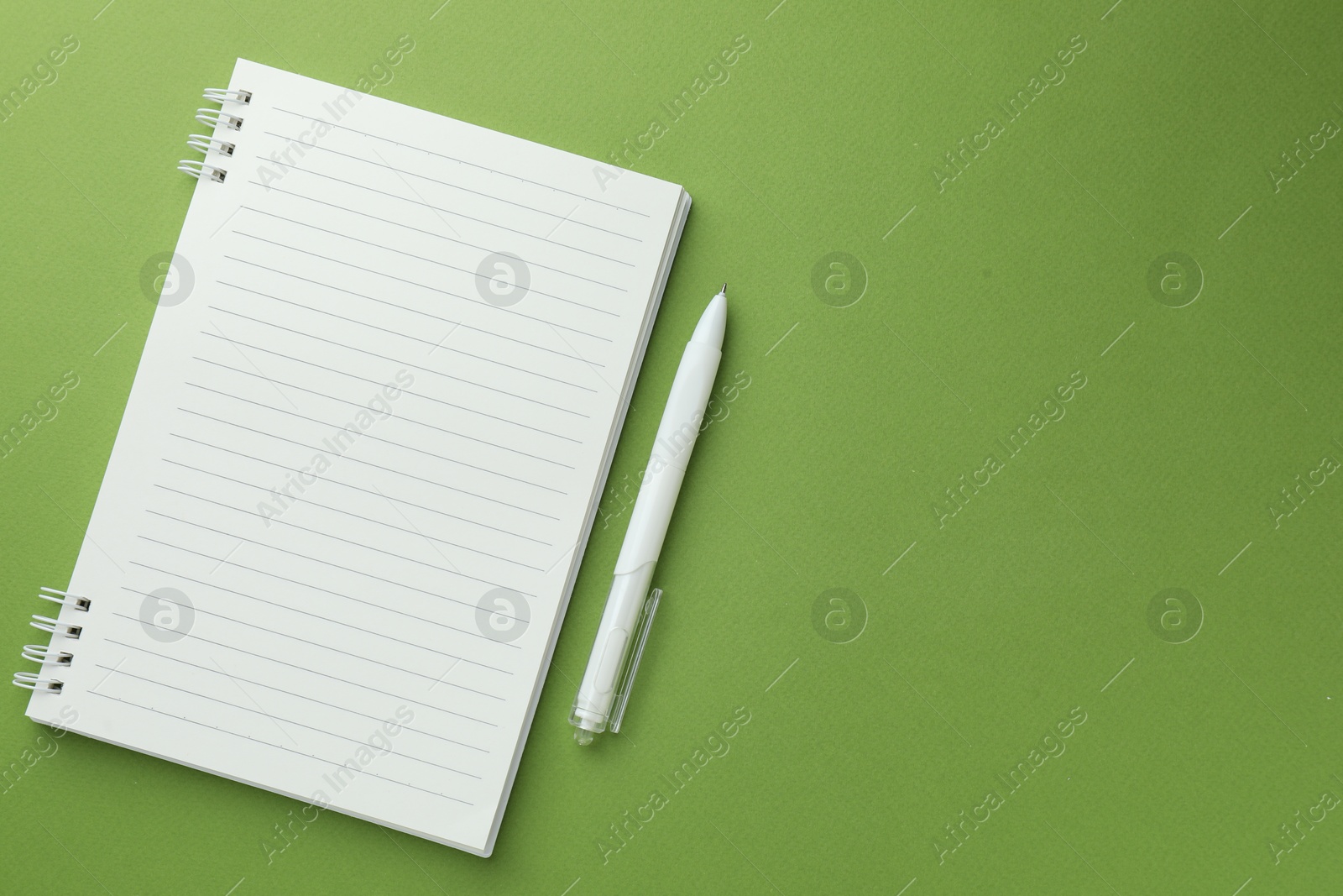 White notebook and pen on green background, flat lay. Space for text Photo of White notebook and pen on green background, flat lay. Space for text