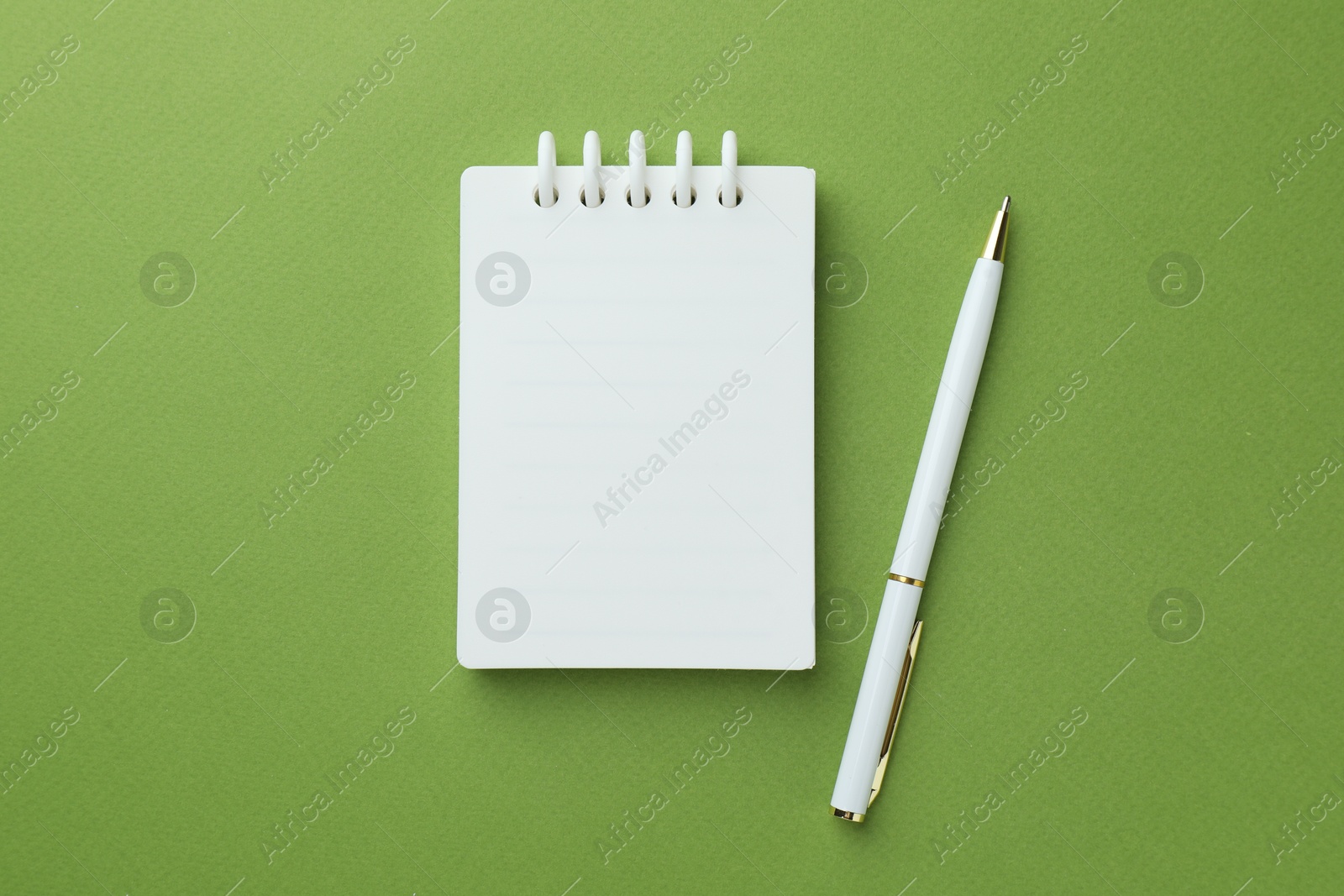 White notebook and pen on green background, flat lay Photo of White notebook and pen on green background, flat lay