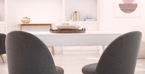 Photo of White table with chairs and decor in stylish dining room, closeup. Interior design