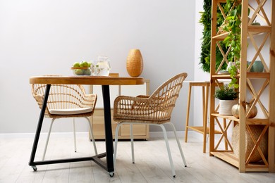 Photo of Wooden table with chairs and decor in stylish dining room. Interior design