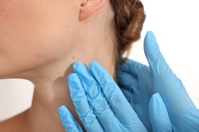 Photo of Doctor examining young woman's mole on white background, closeup