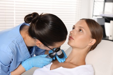 Photo of Doctor examining young woman's mole with dermatoscope in hospital