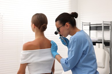 Photo of Doctor examining young woman's mole with dermatoscope in hospital