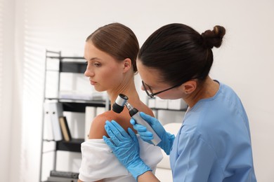 Photo of Doctor examining young woman's mole with dermatoscope in hospital